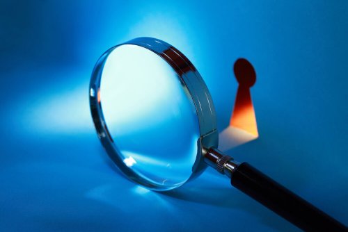 magnifying glass and small keyhole in wall covered in blue light