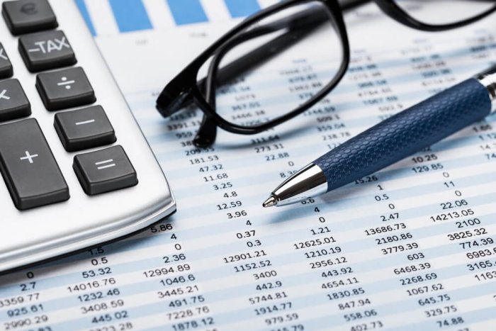 pen, calculator, and glasses on top of a spreadsheet